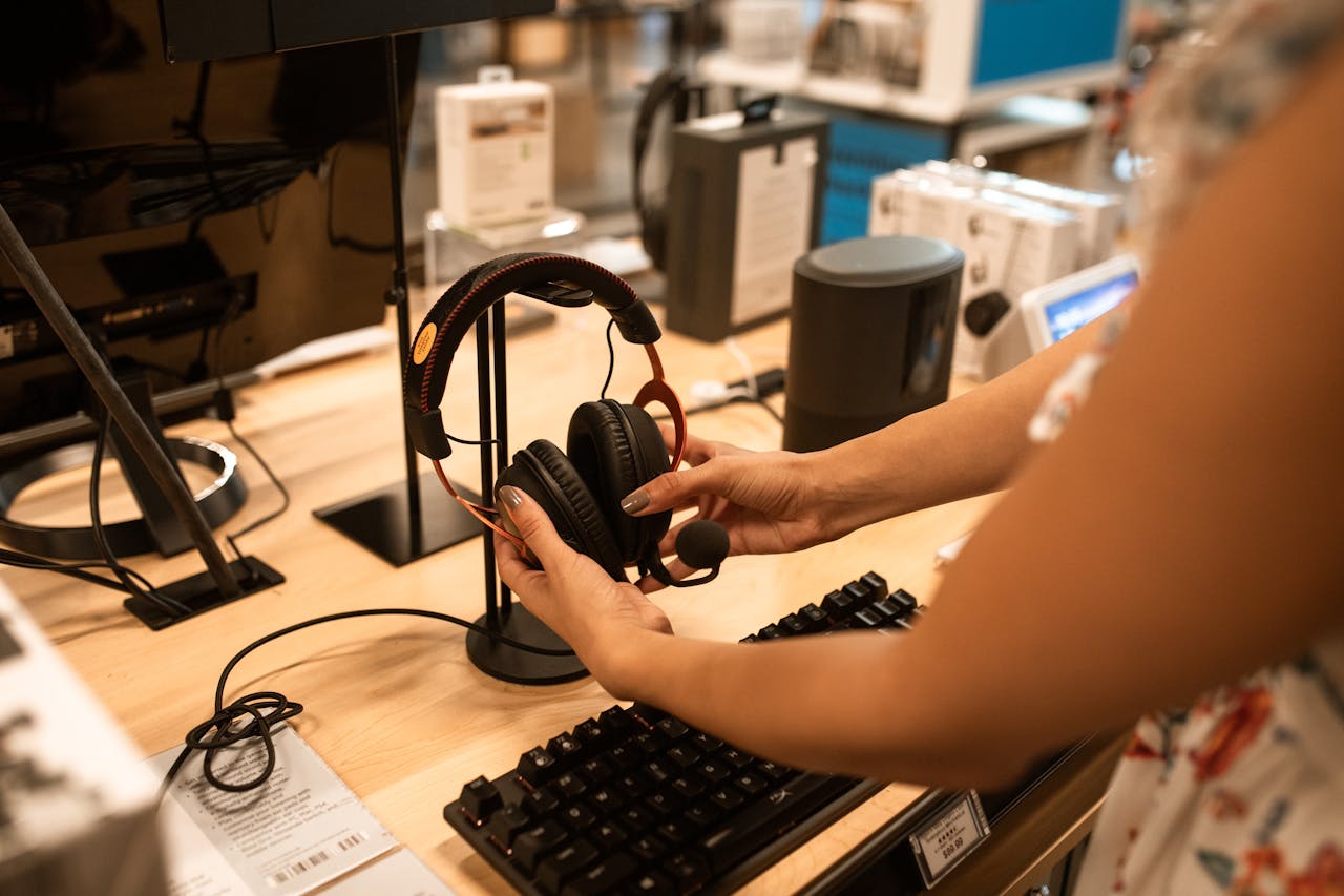 A woman examines headphones in an electronics store, focusing on the audio devices features.
